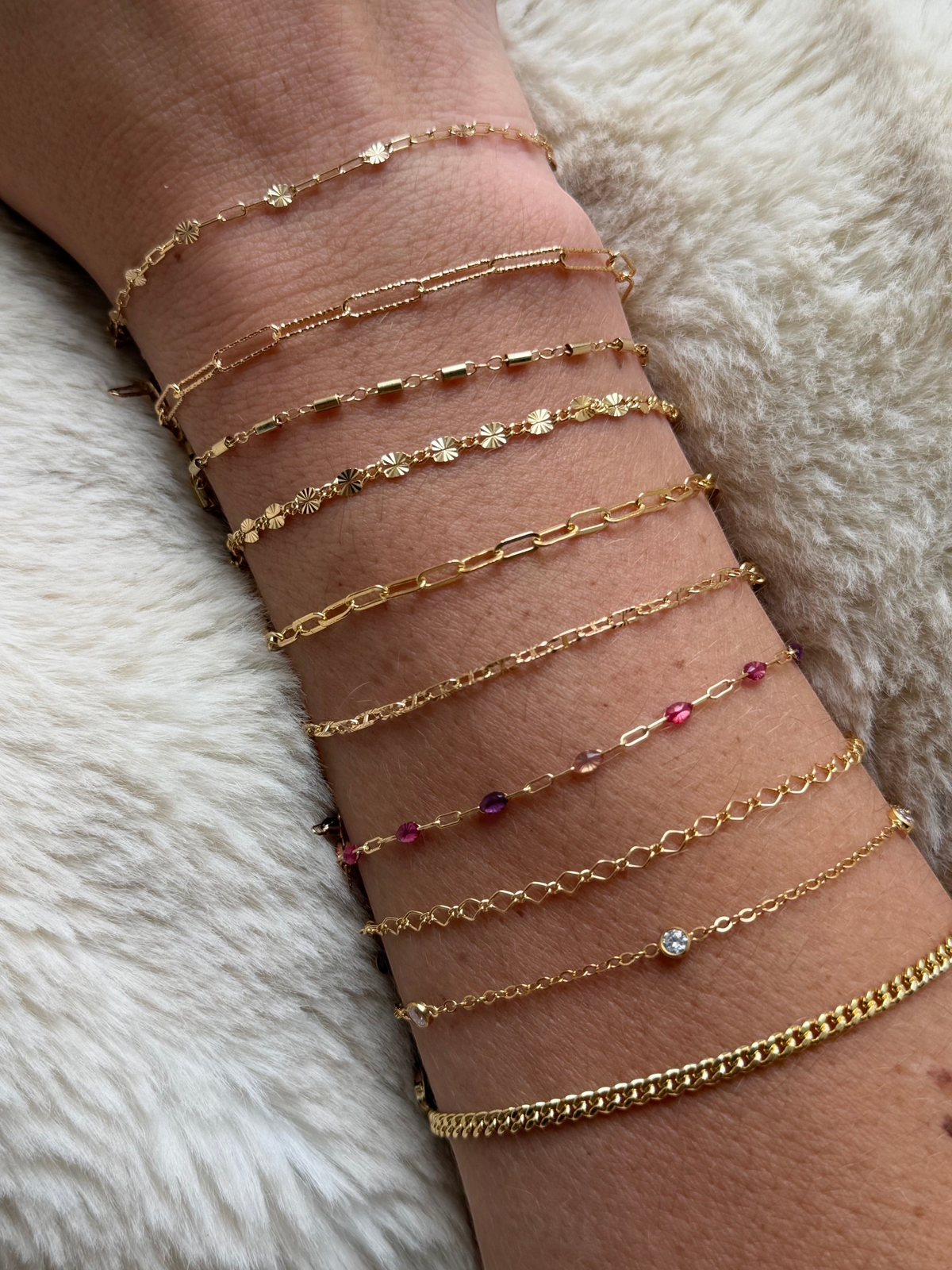 Cuffed by Nano LLC gold filled tube bracelet stack worn on a wrist, featuring various delicate chain designs.